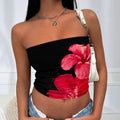 Woman wearing a black strapless top with pink floral design, white bag over shoulder.
