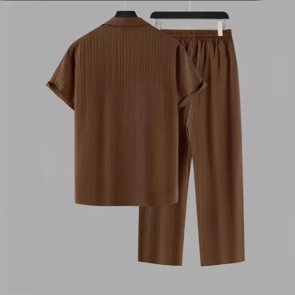 Brown shirt and pants set on hangers against a gray background