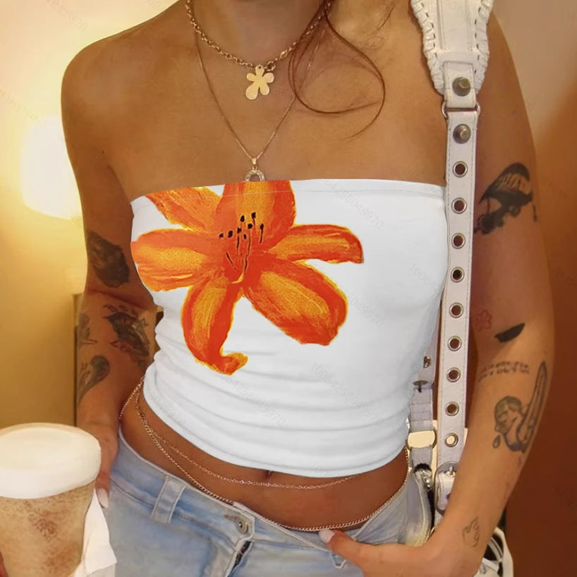 Person wearing a white strapless top with an orange flower design, holding a cup.