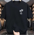 A black short-sleeve crewneck t-shirt with a small white palm tree graphic on the left chest, shown hanging in a clothing store.