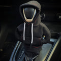 Car gear shift covered with a black hoodie in a car interior.