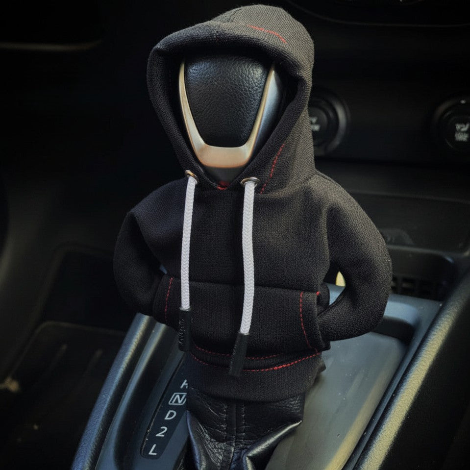 Car gear shift covered with a black hoodie in a car interior.